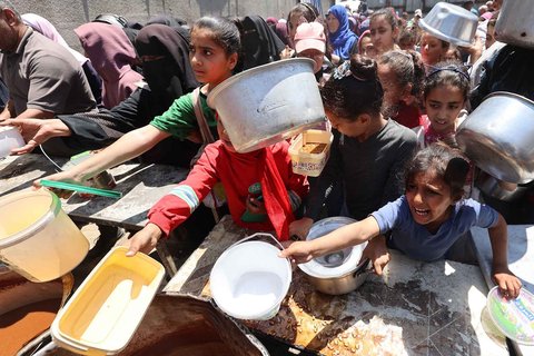 Warga Palestina mengantri untuk mendapatkan makanan hangat di dapur amal di kamp pengungsi Nuseirat di Jalur Gaza bagian tengah, Minggu (04/05/ 2025).