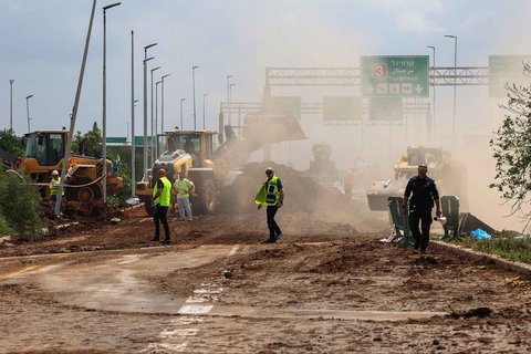 Layanan darurat Israel membersihkan jalan setelah rudal yang diluncurkan dari Yaman menghantam dekat fasilitas tersebut di luar bandara Ben Gurion Israel Minggu (04/05/2025).