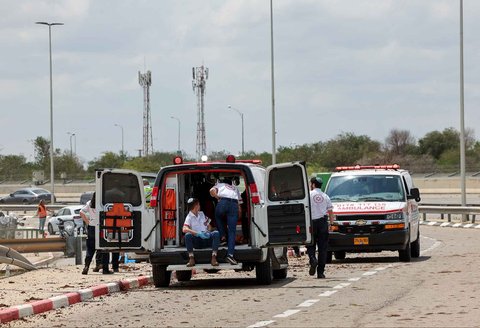 Layanan darurat medis Israel berjaga di jalan yang dipenuhi lumpur setelah rudal yang diluncurkan dari Yaman menghantam dekat fasilitas tersebut di luar bandara Ben Gurion Israel Minggu (04/05/2025).