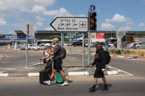 Wisatawan berjalan menuju bandara setelah pintu masuk jalan utama ke fasilitas tersebut ditutup oleh polisi Israel, menyusul aktivasi pertahanan udara terhadap rudal yang diluncurkan dari Yaman di bandara Ben Gurion Israel Minggu (04/05/2025).