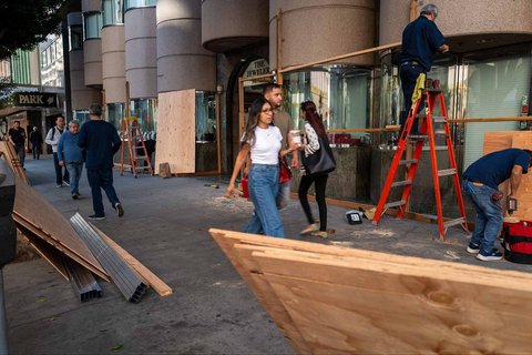 Para pekerja memasang papan kayu lapis  sebagai langkah pengamanan toko dari para penjarah di  pusat kota Los Angeles, Amerika Serikat, (10/06/2025)