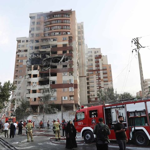 Warga  berkumpul di dekat kendaraan yang rusak akibat serangan Israel, di Teheran, Iran, Jumat (13/06/2025).