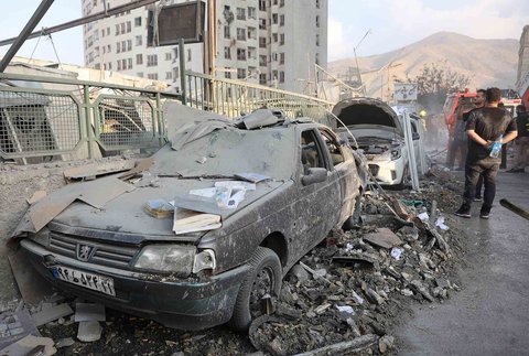 Warga  berkumpul di dekat kendaraan yang rusak akibat serangan Israel, di Teheran, Iran, Jumat (13/06/2025).