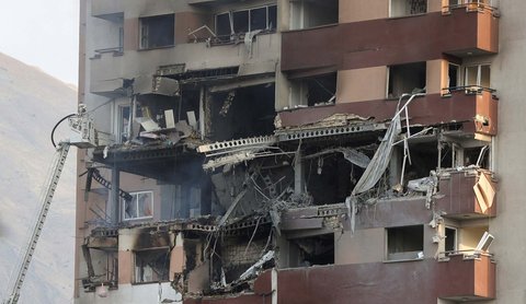 Warga  berkumpul di dekat kendaraan yang rusak akibat serangan Israel, di Teheran, Iran, Jumat (13/06/2025).