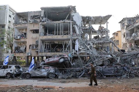 Tentara Israel berjalan melewati bangunan yang rusak parah  terkena rudal yang ditembakkan Iran di kota Ramat Gan, Israel, Sabtu (14/06/2025).