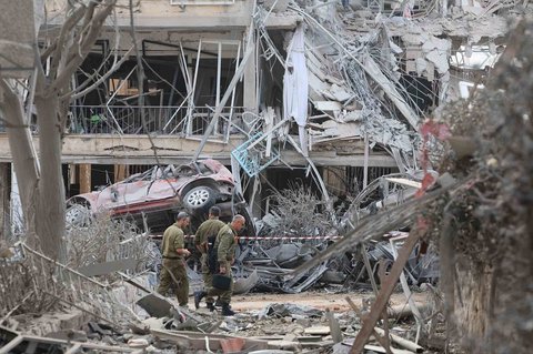 Tentara Israel berjalan melewati bangunan yang rusak parah  terkena rudal yang ditembakkan Iran di kota Ramat Gan, Israel, Sabtu (14/06/2025).