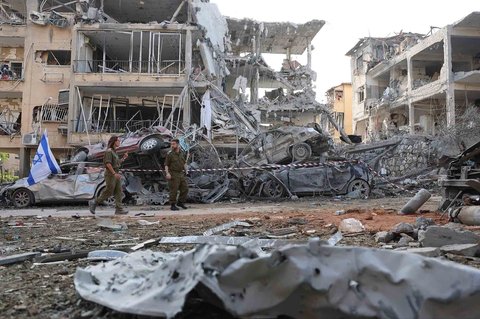 Tentara Israel berjalan melewati bangunan yang rusak parah  terkena rudal yang ditembakkan Iran di kota Ramat Gan, Israel, Sabtu (14/06/2025).