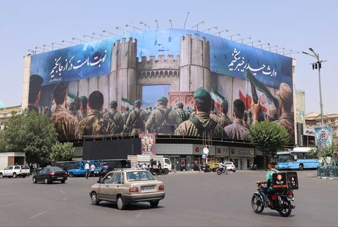 Warga Iran melewati poster anti-Israel di Lapangan Enghlab, Teheran, Sabtu (14/06/2025).