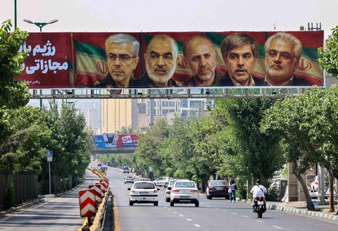 Poster yang menampilkan potret jenderal militer dan ilmuwan nuklir Iran yang tewas dalam serangan Israel terpasang di sebuah jembatan di Teheran,  Sabtu (14/06/2025).