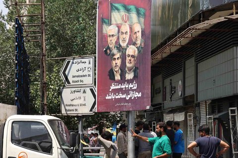 Poster yang menampilkan potret jenderal militer dan ilmuwan nuklir Iran yang tewas dalam serangan Israel terpasang di sudut kota di Teheran,  Sabtu (14/06/2025).
