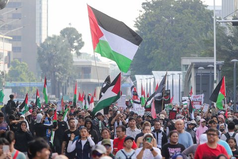 Peserta aksi mengikuti aksi long march dari depan Kedubes Amerika Serikat   hingga Bunderan HI, Jakarta, Minggu (15/06/2025).