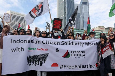 Peserta aksi mengikuti aksi long march dari depan Kedubes Amerika Serikat   hingga Bunderan HI, Jakarta, Minggu (15/06/2025).