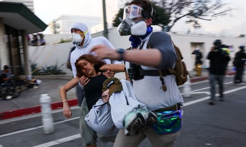 Seorang wanita yang terluka digotong rekannya saat aksi  menentang Presiden AS Donald Trump di Los Angeles, California, AS, Sabtu (14/06/2025) waktu setempat.