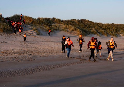 Para migran berlari ke pantai untuk menaiki perahu dalam upaya menyeberangi Selat Inggris di lepas pantai Gravelines, Prancis utara, (16/06/2025).
