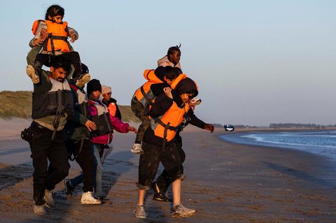 Para migran berlari ke pantai untuk menaiki perahu dalam upaya menyeberangi Selat Inggris di lepas pantai Gravelines, Prancis utara, (16/06/2025).