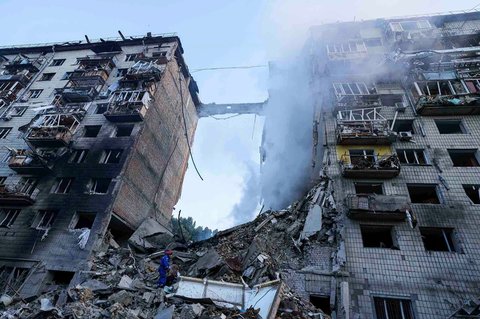 Seorang petugas penyelamat mencari korban selamat di reruntuhan rumah tinggal bertingkat yang hancur akibat serangan Rusia di Kyiv, Selasa, (17/06/2025).<br />AP/ Evgeniy Maloletka