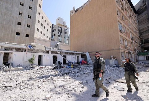 Tentara Israel berjalan di tengah puing-puing di luar Rumah Sakit Soroka yang terkena rudal Iran di Beersheba, Israel, (19/06/2025)