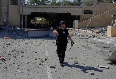Tim tanggap darurat Israel memperingatkan warga di lokasi serangan rudal  Iran  di Haifa, Israel, Jumat (20/06/2025).<br /> AP/Baz Ratner