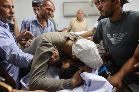 Keluarga  berduka di dekat jenazah warga Palestina yang tewas sehari sebelumnya akibat tembakan Israel saat antri mendapatkan bantuan pangan, di kamar mayat rumah sakit Al-Shifa di Kota Gaza, Rabu (18/06/2025).