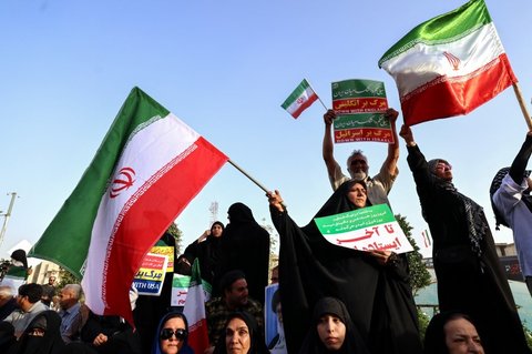 Warga Iran meneriakkan slogan dan mengibarkan bendera saat merayakan gencatan senjata antara Iran dan Israel di Lapangan Enghelab, Teheran, pada Selasa (24/6/2025).