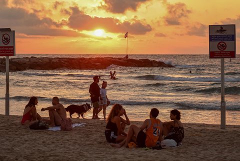 Aktifitas warga Israel saat matahari terbenam (sunset)  usai gencatan senjata yang mengakhiri perang dengan Iran  di pantai di Tel Aviv, Israel (24/06/2025).