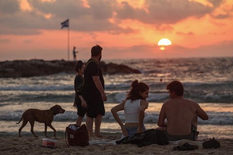 Aktifitas warga Israel saat matahari terbenam (sunset)  usai gencatan senjata yang mengakhiri perang dengan Iran  di pantai di Tel Aviv, Israel (24/06/2025).