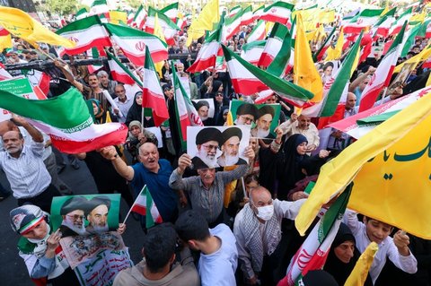 Warga Iran meneriakkan slogan dan mengibarkan bendera saat merayakan gencatan senjata antara Iran dan Israel di Lapangan Enghelab, Teheran, pada Selasa (24/6/2025).