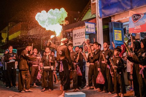 Seorang pemuda  melakukan atraksi menyemburkan api saat pawai yang menandai dimulainya Tahun Baru Islam 1 Muharram 1447 Hijriah di Surabaya, (26/06/2025).