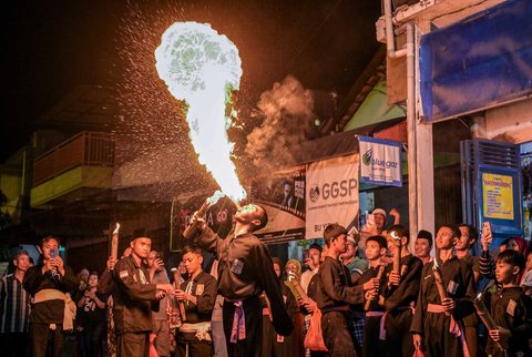 Seorang pemuda  melakukan atraksi menyemburkan api saat pawai yang menandai dimulainya Tahun Baru Islam 1 Muharram 1447 Hijriah di Surabaya, (26/06/2025).