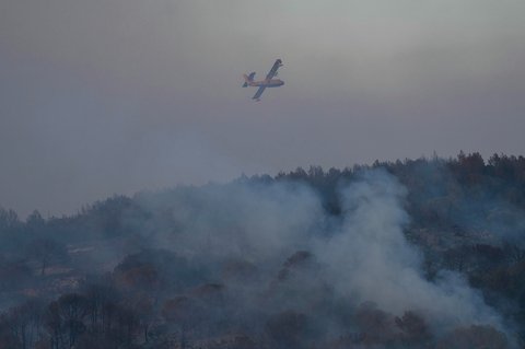 Sebuah pesawat pemadam kebakaran udara Canadair CL-415 milik Pertahanan Sipil Prancis (Securite Civile) terbang di langit yang dipenuhi asap selama kebakaran hutan di dekat Bizanet, Prancis barat daya, , (29/06/2025).