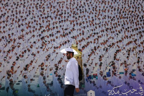 Seorang pria mengenakan topi payung untuk melindungi dirinya dari terik matahari di Kota Suci Mekkah, Arab Saudi, pada 2 Juni 2025. Lebih dari satu juta peziarah membanjiri kota suci Mekkah menjelang haji tahunan, dengan pihak berwenang berjanji untuk menyelenggarakan ibadah haji yang lebih aman di cuaca panas mendidih.