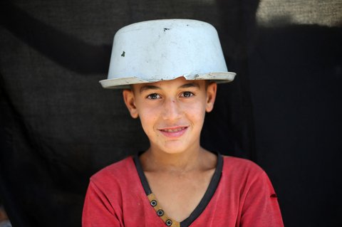 Seorang anak Palestina menutupi kepalanya dengan panci  kosong saat menunggu di titik distribusi makanan hangat di Nuseirat di Jalur Gaza bagian tengah, (04/06/2025).