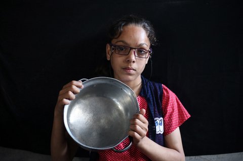 Seorang anak  Palestina memegang panci kosong sambil menunggu di titik distribusi makanan hangat di Nuseirat di Jalur Gaza bagian tengah, (04/06/2025)