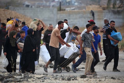 Warga Gaza membawa paket bantuan bahan  makanan dari Yayasan Kemanusiaan Gaza (GHF), sebuah kelompok bantuan swasta yang didukung AS, di Jalur Gaza bagian tengah, Minggu (08/08/2025).