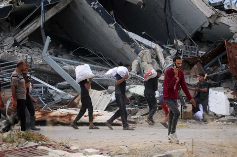 Warga Gaza membawa paket bantuan bahan  makanan dari Yayasan Kemanusiaan Gaza (GHF), sebuah kelompok bantuan swasta yang didukung AS, di Jalur Gaza bagian tengah, Minggu (08/08/2025).