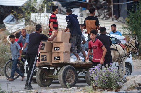 Warga Gaza membawa paket bantuan bahan  makanan dari Yayasan Kemanusiaan Gaza (GHF), sebuah kelompok bantuan swasta yang didukung AS, di Jalur Gaza bagian tengah, Minggu (08/08/2025).