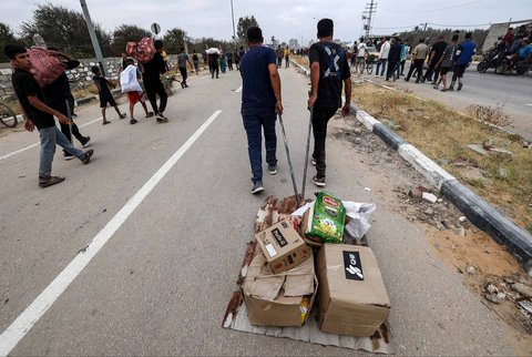 Warga Gaza membawa paket bantuan bahan  makanan dari Yayasan Kemanusiaan Gaza (GHF), sebuah kelompok bantuan swasta yang didukung AS, di Jalur Gaza bagian tengah, Minggu (08/08/2025).