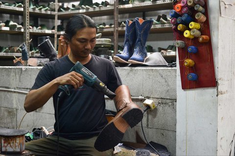 Perajin sedang mengerjakan sepasang sepatu bot kulit untuk pasar AS di bengkel Tegep Boots di Bandung, Jawa Barat, Selasa (15/07/2025).