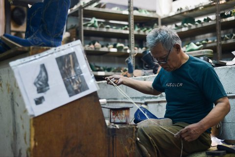 Perajin sedang mengerjakan sepasang sepatu bot kulit untuk pasar AS di bengkel Tegep Boots di Bandung, Jawa Barat, Selasa (15/07/2025).