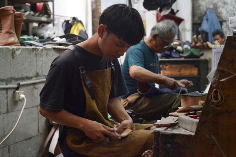 Perajin sedang mengerjakan sepasang sepatu bot kulit untuk pasar AS di bengkel Tegep Boots di Bandung, Jawa Barat, Selasa (15/07/2025).
