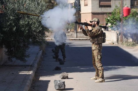 Anggota pasukan keamanan Suriah menembakkan senjata di tengah bentrokan antara pejuang Druze dan suku Badui di kota Suwayda, Suriah, Rabu (16.07/2025).