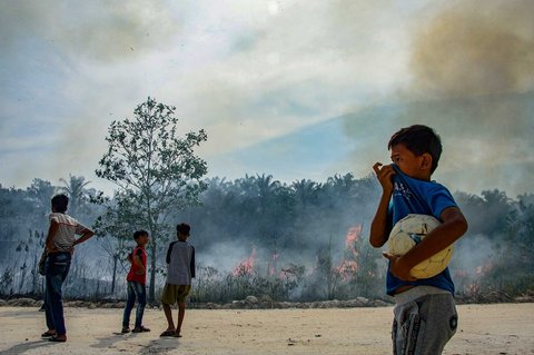 Anak-anak menyaksikan  kebakaran hutan di Karya Indah, Provinsi Riau, Sabtu (19/07/2025).