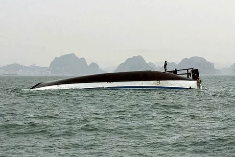 Seorang pria berdiri di atas kapal wisata yang terbalik di Teluk Ha Long, Provinsi Quang Ninh, Vietnam, Sabtu (19/07/2025).