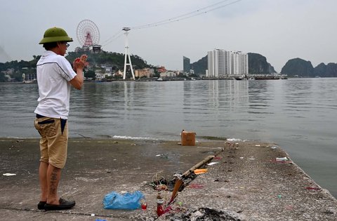 Seorang pria berdoa untuk para korban kapal wisata yang terbalik di Teluk Ha Long, Provinsi Quang Ninh, Vietnam, Minggu (20/07/2025).