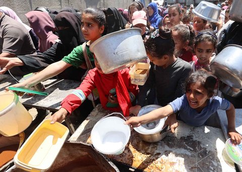 Warga Palestina mengantri untuk mendapatkan makanan hangat di dapur amal di kamp pengungsi Nuseirat di Jalur Gaza bagian tengah, Minggu (04/05/ 2025).