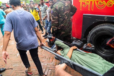 Petugas pemadam kebakaran dan keamanan Bangladesh melakukan proses evakuasi  setelah sebuah jet latih Angkatan Udara jatuh di sebuah sekolah di Dhaka, Bangladesh, Senin (21/07/2025).