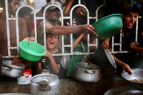 Anak-anak Palestina menunggu makanan di dapur amal di daerah Mawasi, Khan Yunis, Jalur Gaza Selatan, Selasa (22/07/2025).<br />AFP