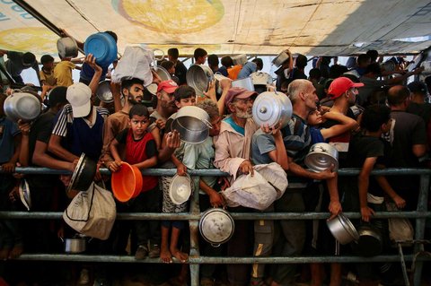Anak-anak Palestina menunggu makanan di dapur amal di daerah Mawasi, Khan Yunis, Jalur Gaza Selatan, Selasa (22/07/2025).<br />AFP
