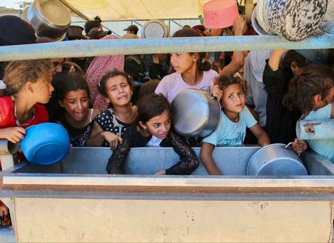 Anak-anak Palestina menunggu makanan di dapur amal di daerah Mawasi, Khan Yunis, Jalur Gaza Selatan, Selasa (22/07/2025).<br />AFP