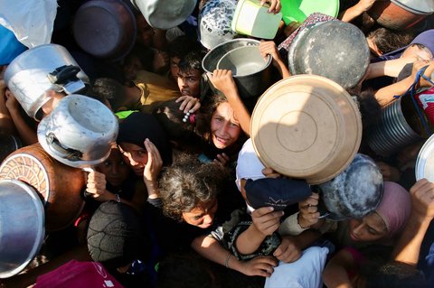 Anak-anak Palestina menunggu makanan di dapur amal di daerah Mawasi, Khan Yunis, Jalur Gaza Selatan, Selasa (22/07/2025).<br />AFP